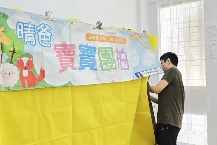 晴爸在攝影棚掛上「晴爸寶寶團拍」布條，準備第一場寶寶團拍