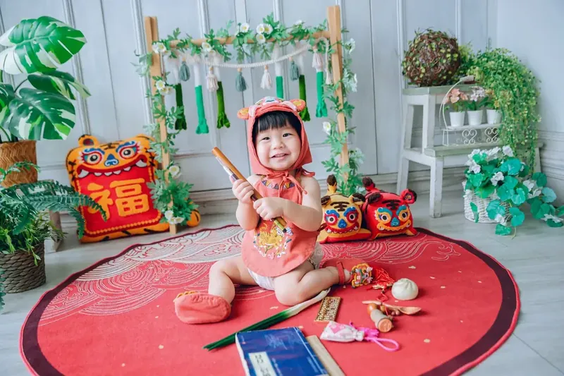 晴爸實拍:穿手工虎衣的寶貝坐在紅色抓周墊上,拿著笛子笑開