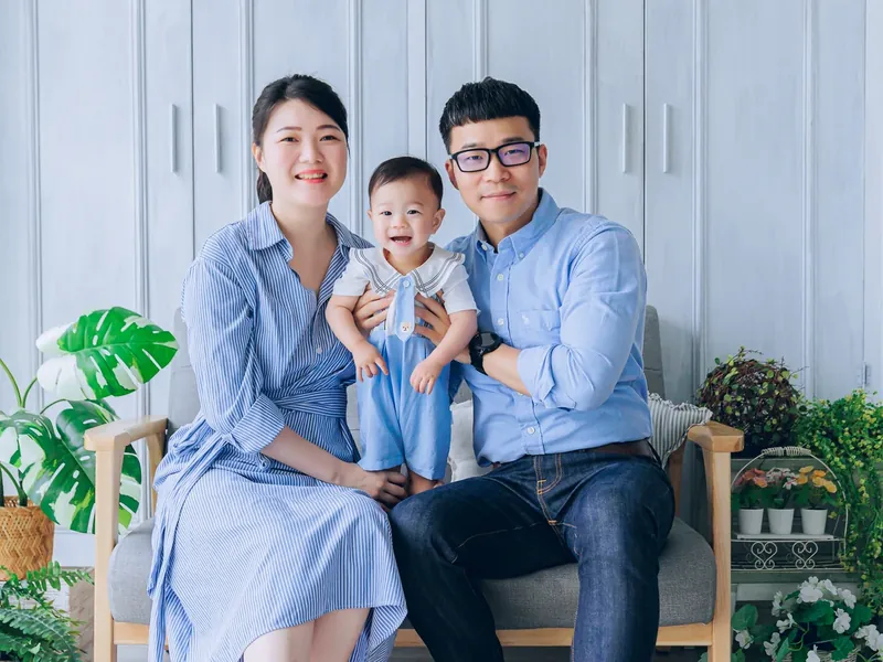 爸媽抱著寶貝在沙發上拍小家庭合照