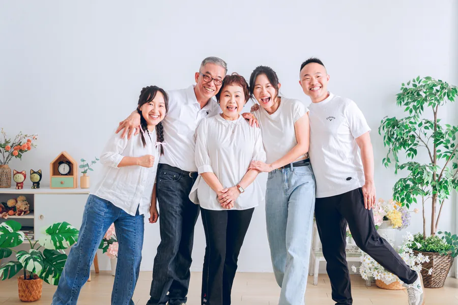 爸媽和三個已經長大的孩子一起開心大笑的全家福